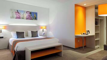 Habitació d'hotel moderna amb llit, tauletes de nit, escriptori i una paret d'accent taronja vibrant.