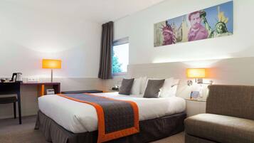 A hotel room with a bed, a desk, a chair, and a painting of the Statue of Liberty.