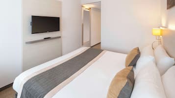 Une chambre d’hôtel équipée d’un lit, d’un téléviseur à écran plat fixé au mur, d’une table de chevet et d’une lampe.