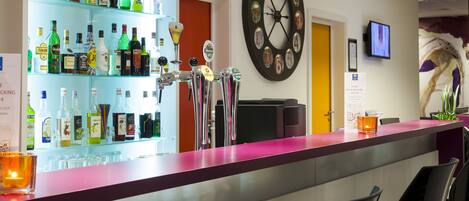 A bar area with a variety of liquor bottles, a dartboard, and a clock on the wall.