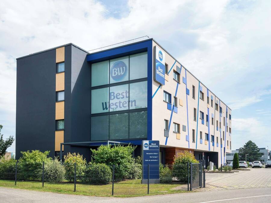 A modern hotel building with a prominent 'Best Western' sign, a reception area, and a parking lot.