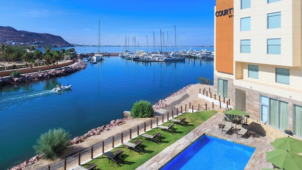 Un puerto deportivo con barcos, una piscina y un edificio con la leyenda "COURTYARD".