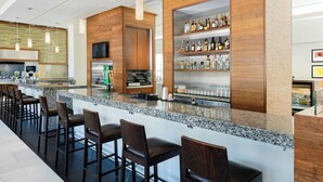 Una zona de bar moderna con encimera de granito, taburetes de madera y una vitrina para vinos y licores.