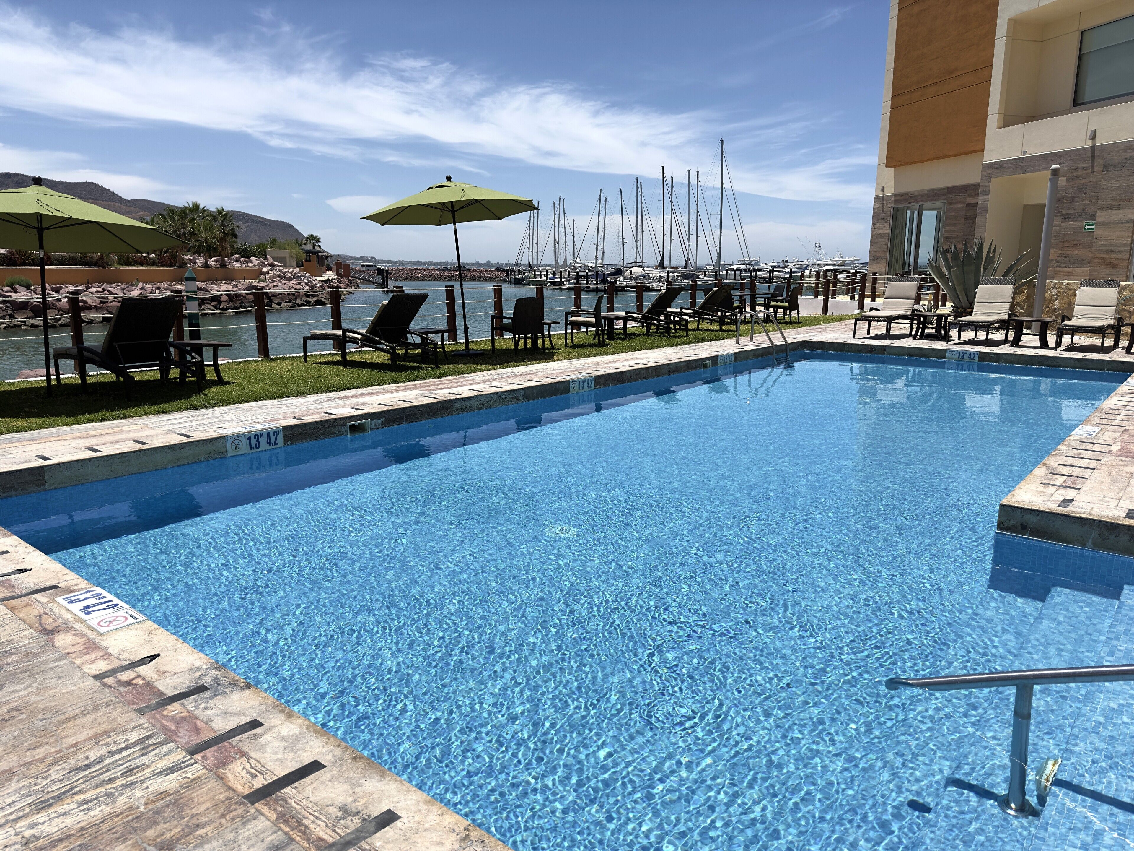 A pool area with clear blue water, lounge chairs, and umbrellas.