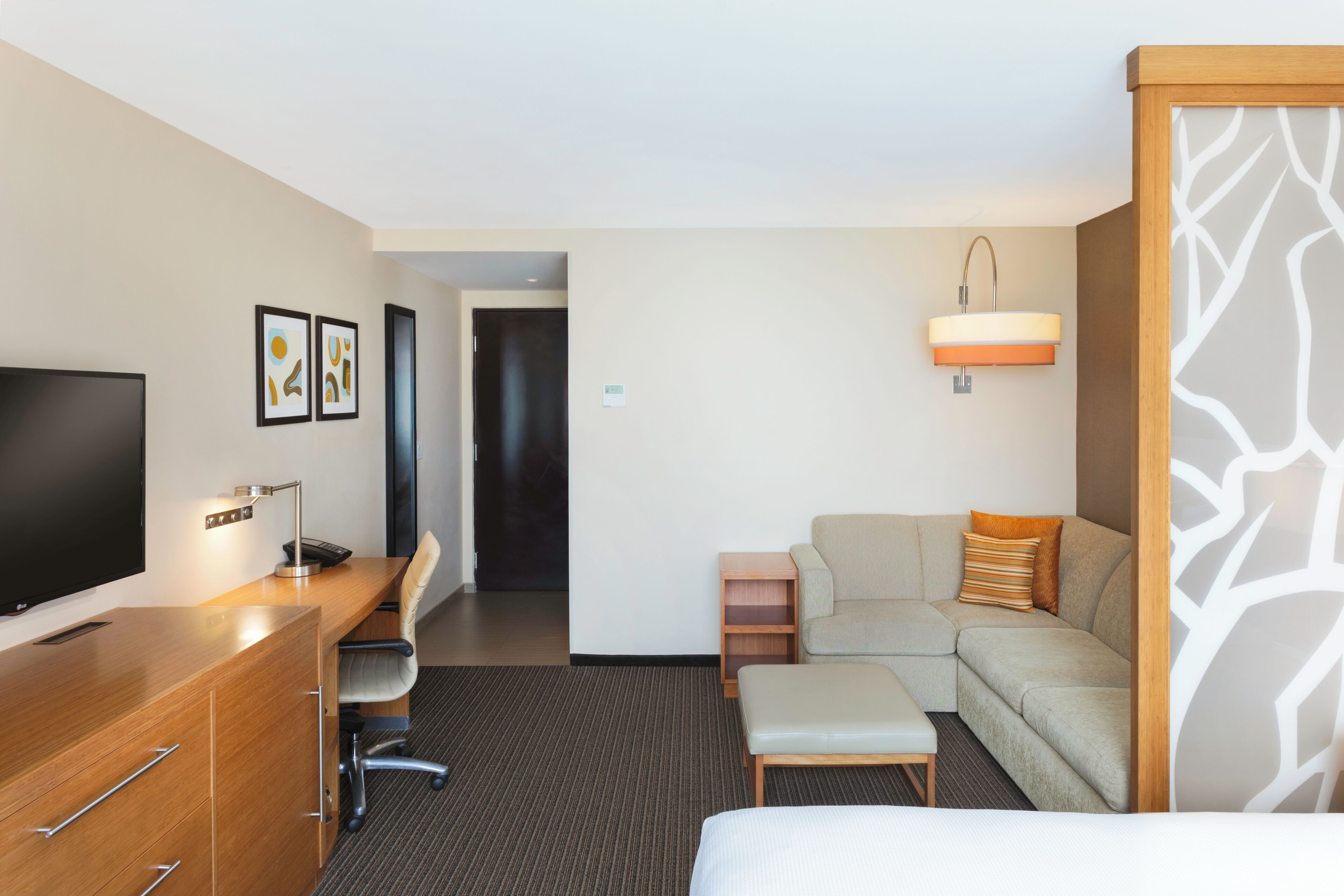 Una habitación de hotel con una cama, un escritorio con televisor, un sofá y una mesita.
