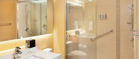 A modern bathroom with a glass-enclosed shower, a white sink, and a large mirror.