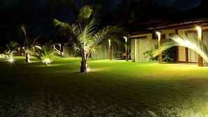A well-lit outdoor area with palm trees and a building with large windows. - Gungaporanga Hotel (Barra de São Miguel)