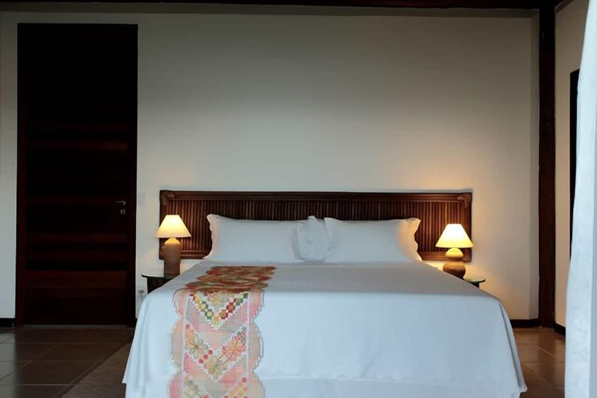 A neatly made bed with a white bedspread and a colorful blanket, flanked by two bedside lamps.