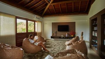 A spacious living room with large bean bags, a flat-screen TV, and a bookshelf.