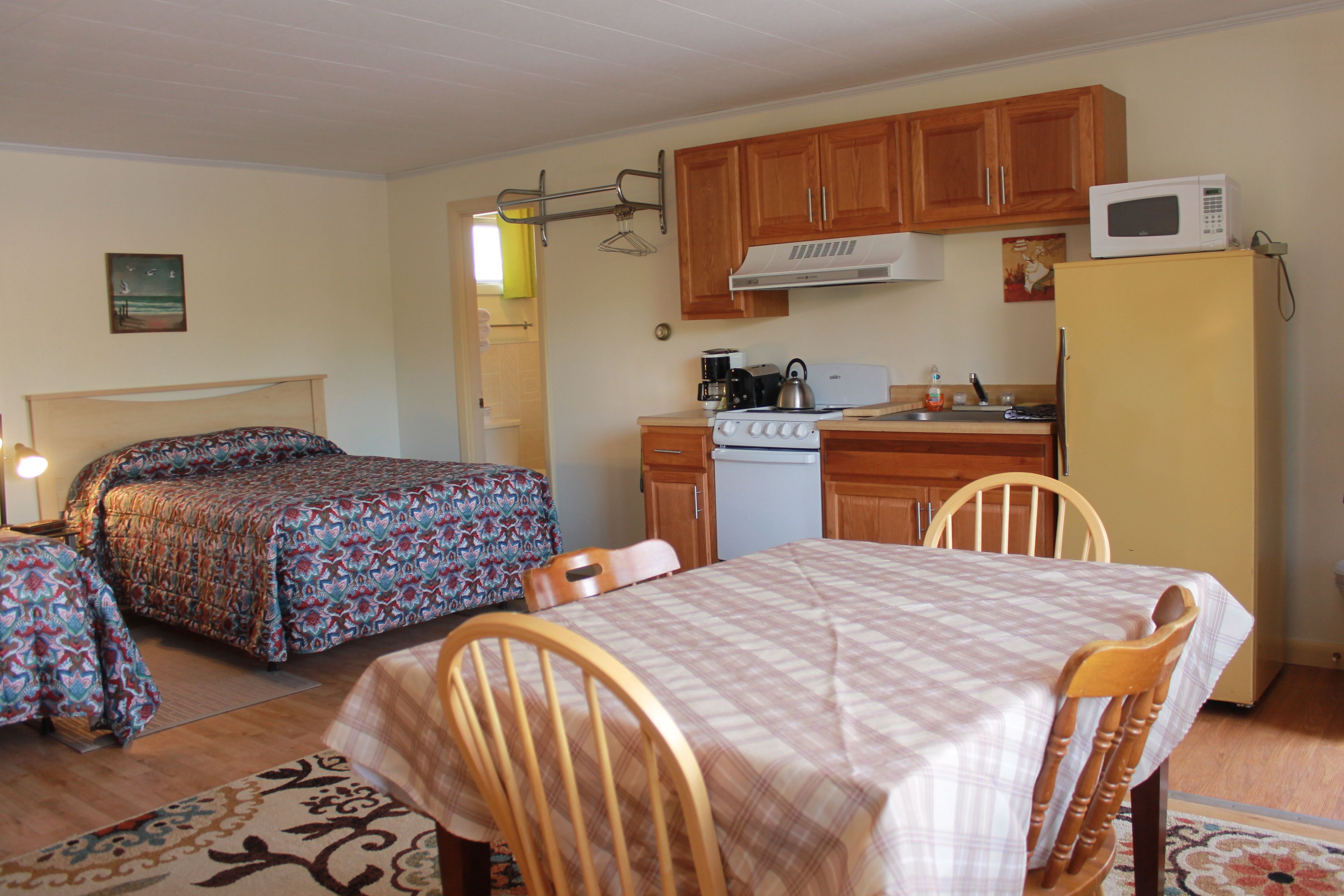 A compact room with a bed, a dining table, and a kitchenette.