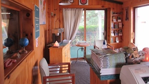 A wooden cabin interior with a desk, chair, coffee machine, and a window with a view of greenery. - Acadia Gateway Motel (Trenton)