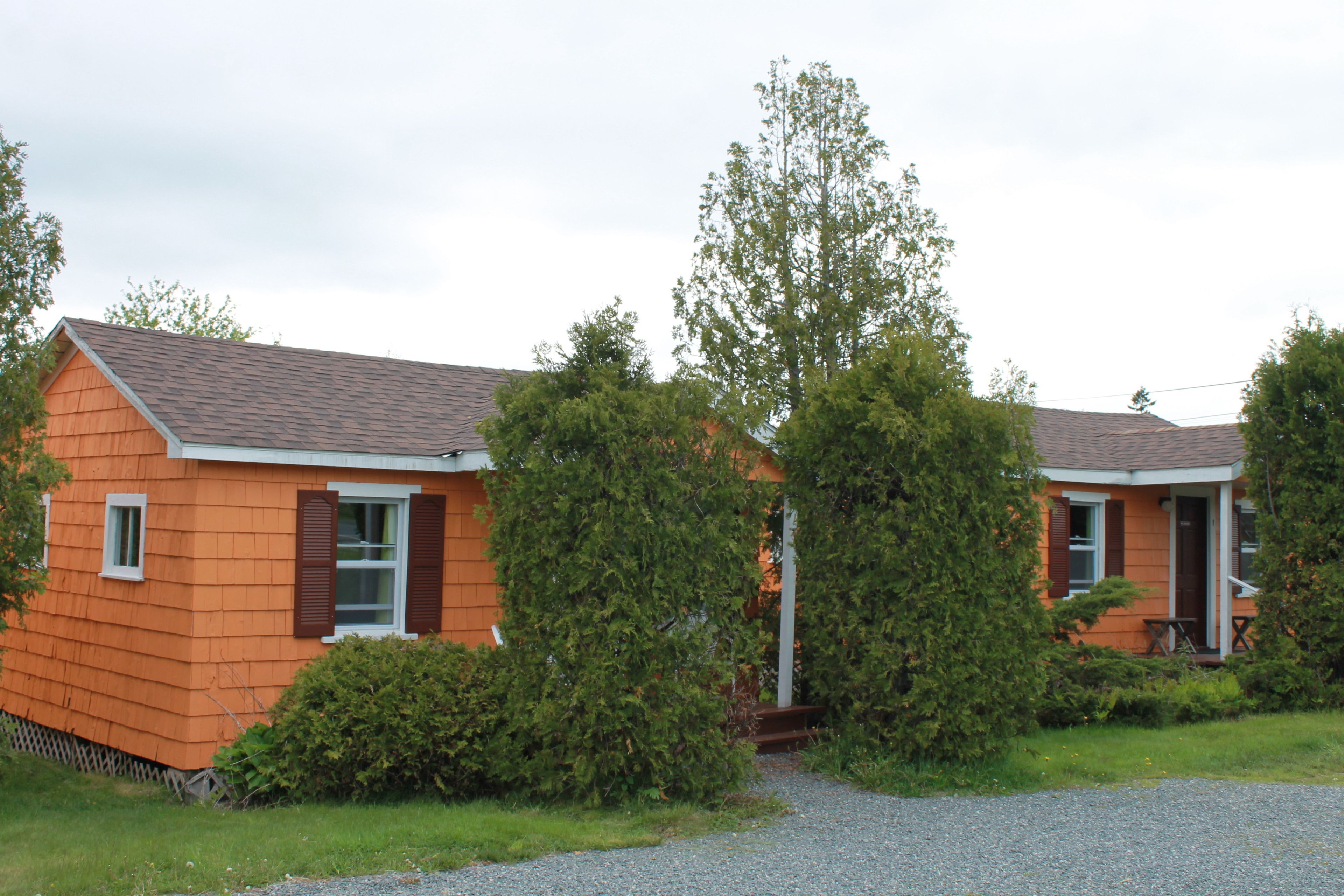 Une rangée de maisons mobiles orange, avec une allée en gravier et des espaces verts aménagés.