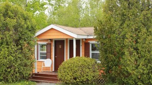 A small, single-story house with a porch, a door marked with the number 10, and a chair outside. - Acadia Gateway Motel (Trenton)