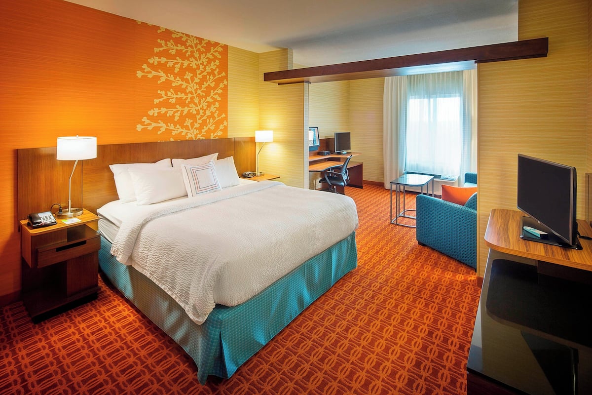 A hotel room with a large bed, a desk, a chair, and a TV.
