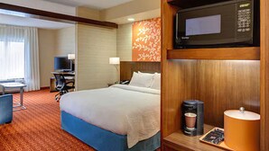A hotel room with a bed, a desk, a television, and a microwave.