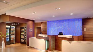 A reception area with a counter, a refrigerator stocked with beverages, and a wall with a blue abstract design. - Fairfield Inn & Suites Monaca (Monaca)