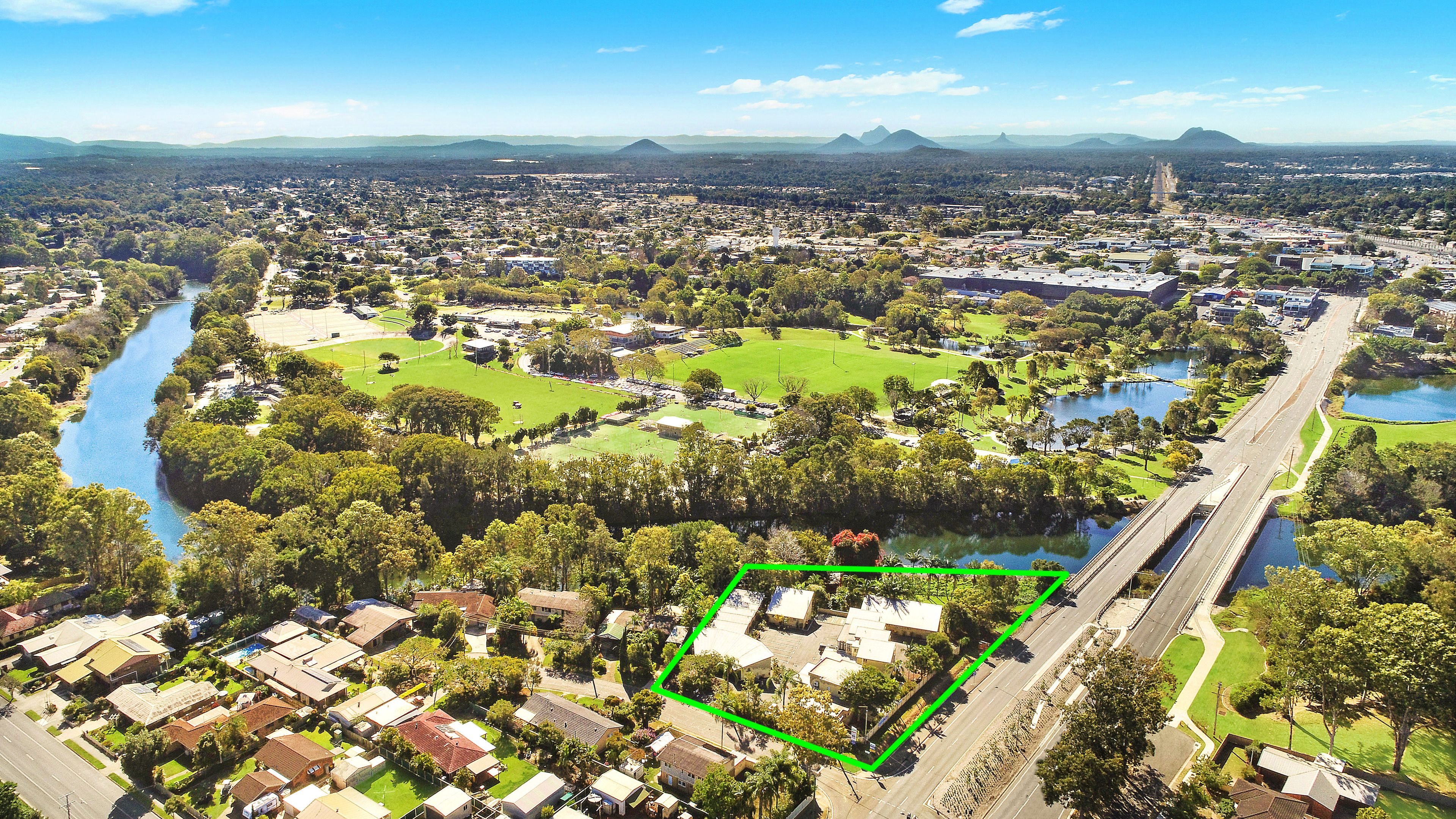 An aerial view of a residential area with houses, a river, and green spaces.