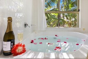A bathtub with rose petals, a bottle of champagne, and a glass of champagne. - Caboolture Riverlakes Motel (Caboolture South)