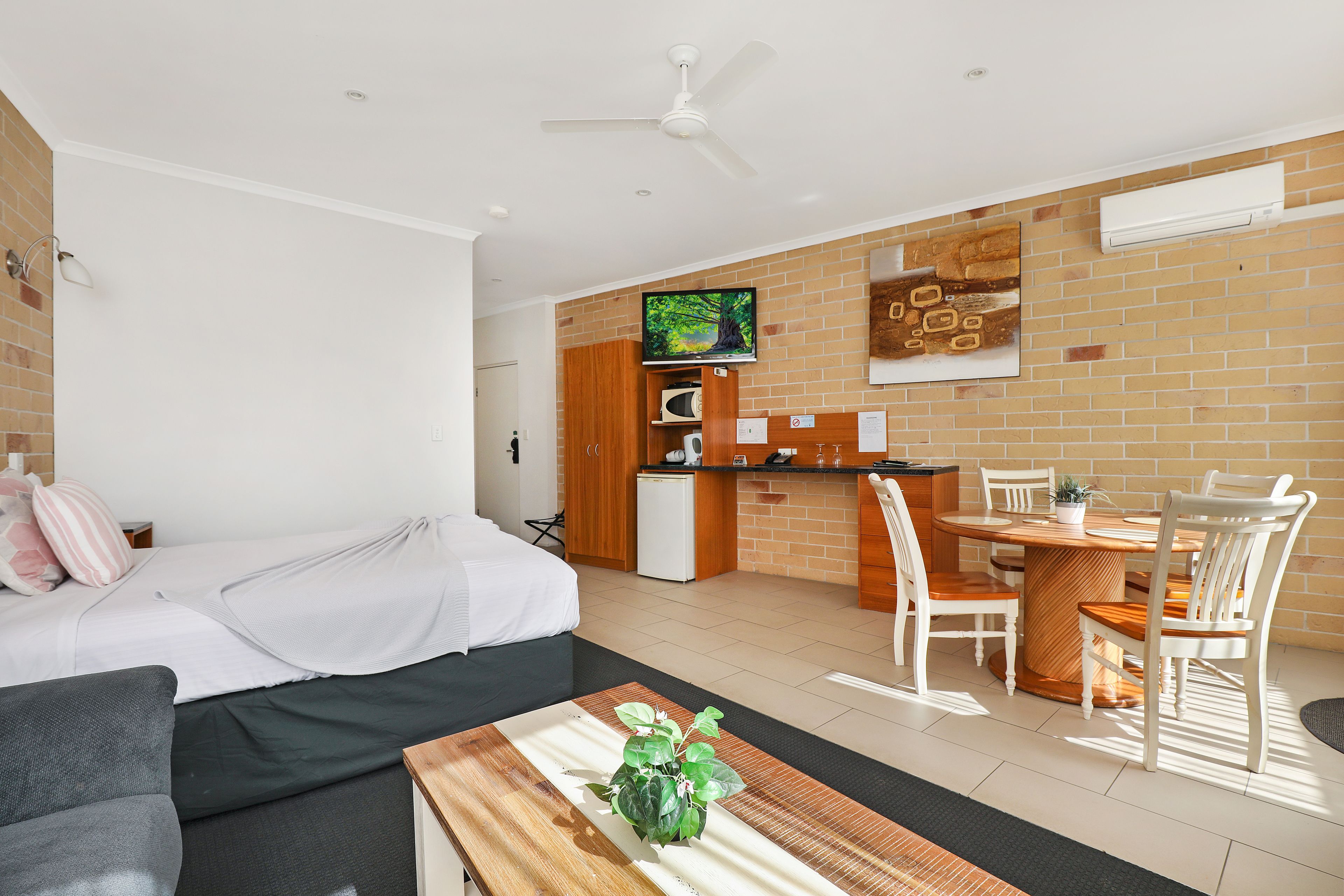 A modern living room with a sofa, a coffee table with a plant, and a dining area with a table and chairs.