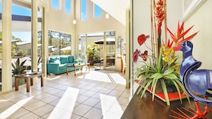 A spacious living area with a sofa, coffee table, and potted plants.