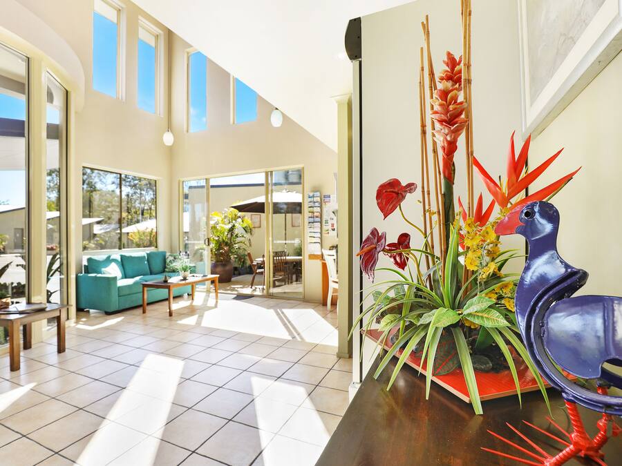 A spacious living area with a sofa, coffee table, and potted plants.