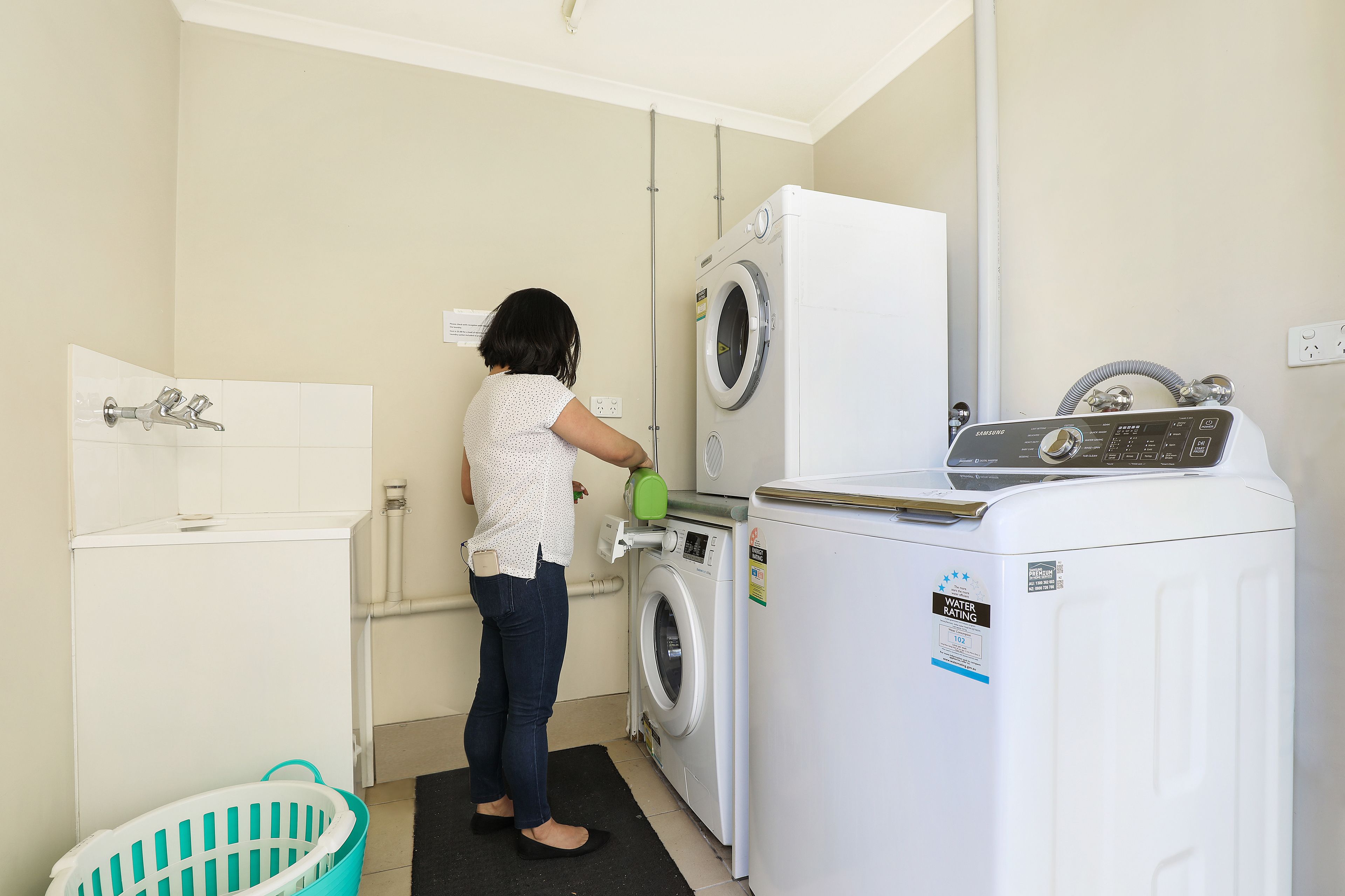 A laundry area with a washing machine, a dryer, and a washing machine with a water rating label.
