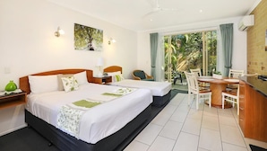 A hotel room with two beds, a dining area, and a view of the outdoors.