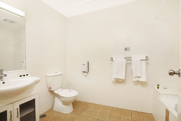 Un baño con inodoro, lavamanos y barra para toallas.