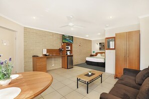 A compact hotel room with a kitchenette, a dining area, a sofa, and a bed.
