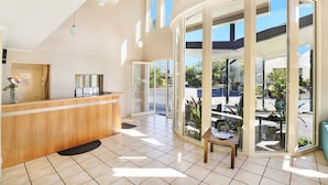 A reception area with a wooden counter, a small table with a vase, and large glass doors leading outside.
