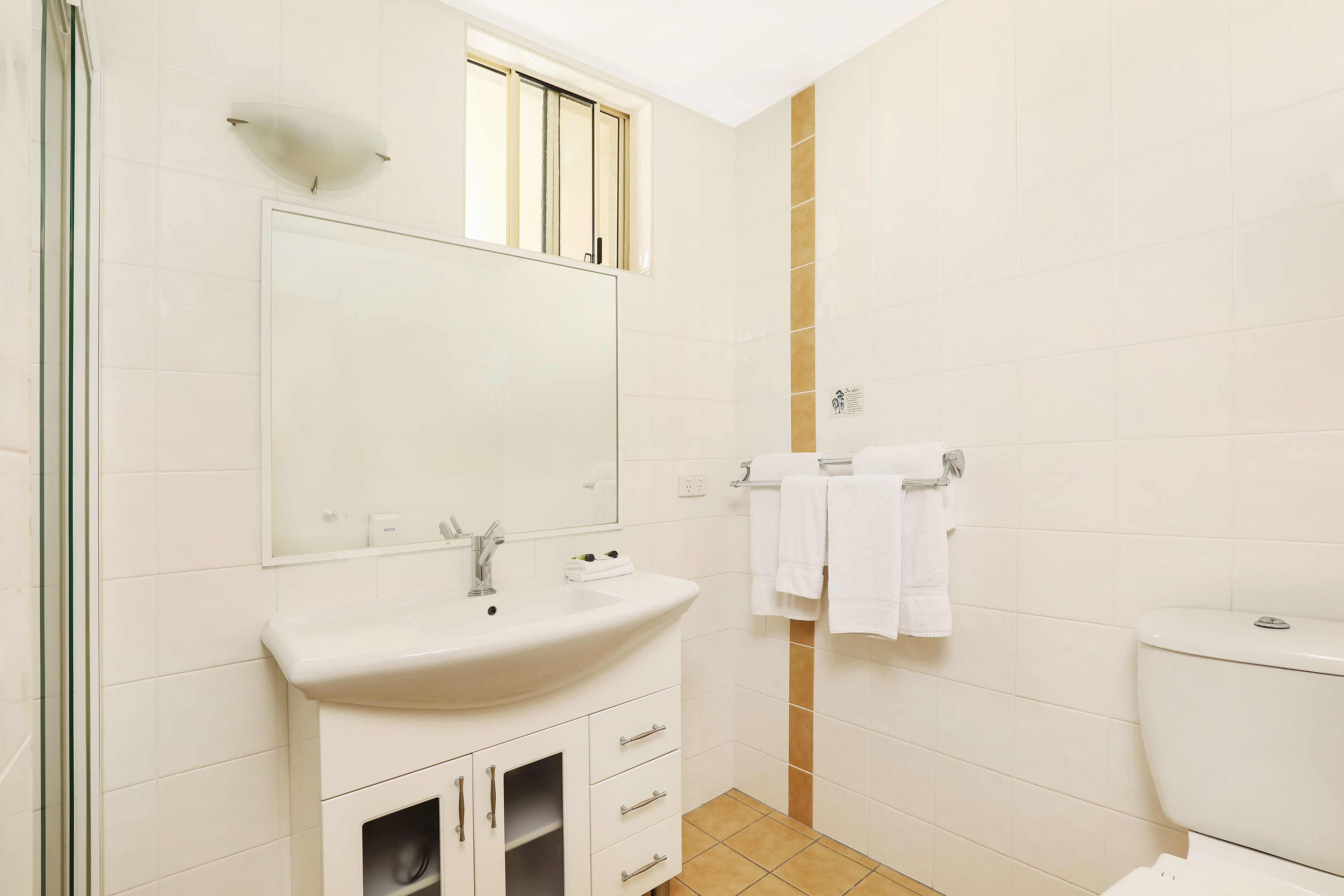 A bathroom with a white sink, mirror, and toilet.