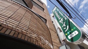 A building with a brick facade and a green signboard with Japanese text.