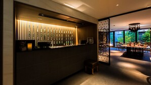 A modern interior with a reception desk, a wooden partition with vertical slats, and a dining area with tables and chairs.