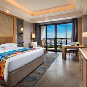 Une chambre d’hôtel avec un grand lit, un bureau, une chaise, un balcon avec vue et une grande fenêtre.