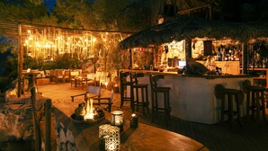 An outdoor bar area with wooden furniture, a thatched roof, and string lights. - Perdue Hotel (Fethiye)