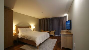 Une chambre d’hôtel avec un lit en bois, une télévision, un bureau et une chaise.
