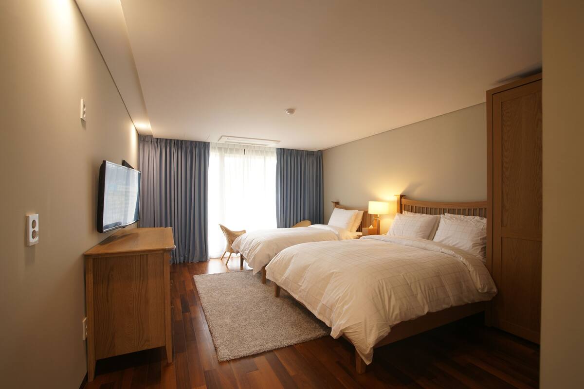 A hotel room with two beds, a TV, a desk, and a chair.