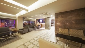 Un lobby moderno con una zona de estar, un mostrador de recepción y vistas a la ciudad de noche.