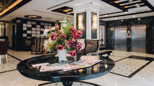 Un comptoir d’accueil agrémenté d’un vase de fleurs, de magazines et doté d’un aménagement intérieur moderne.