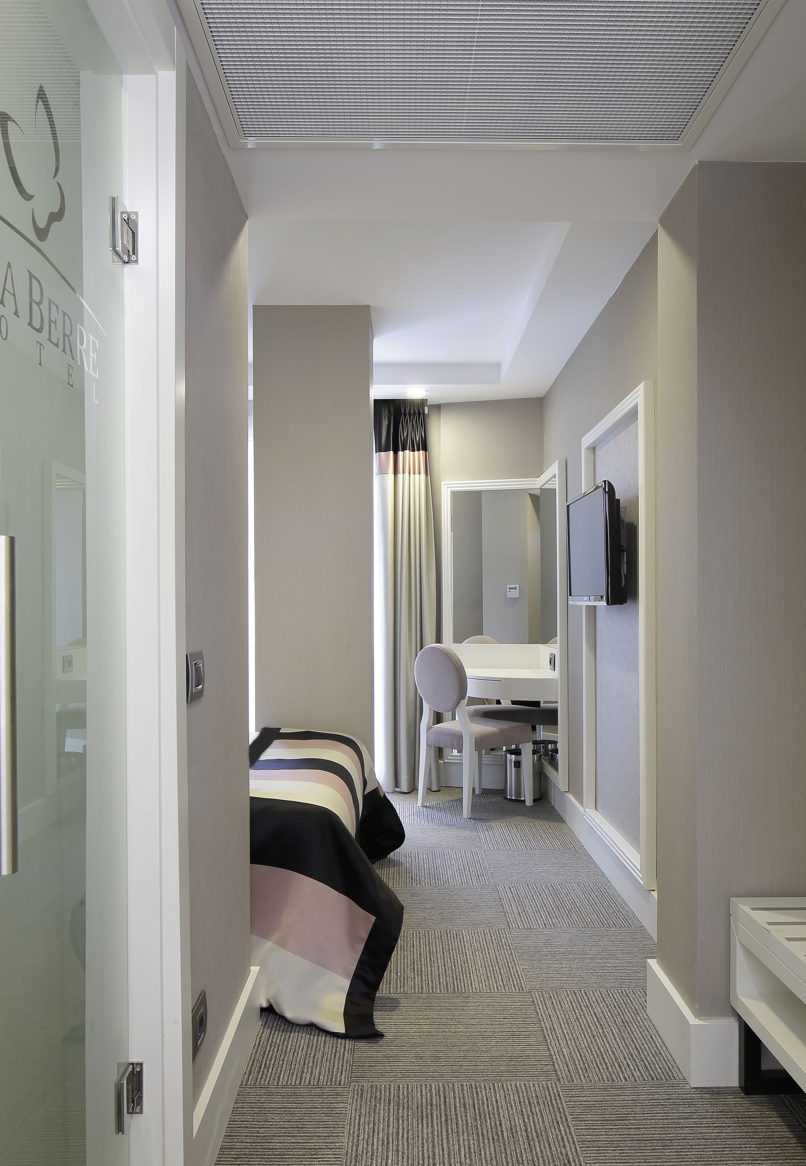 A hotel room with a bed, a desk, a chair, a television, and a mirror.