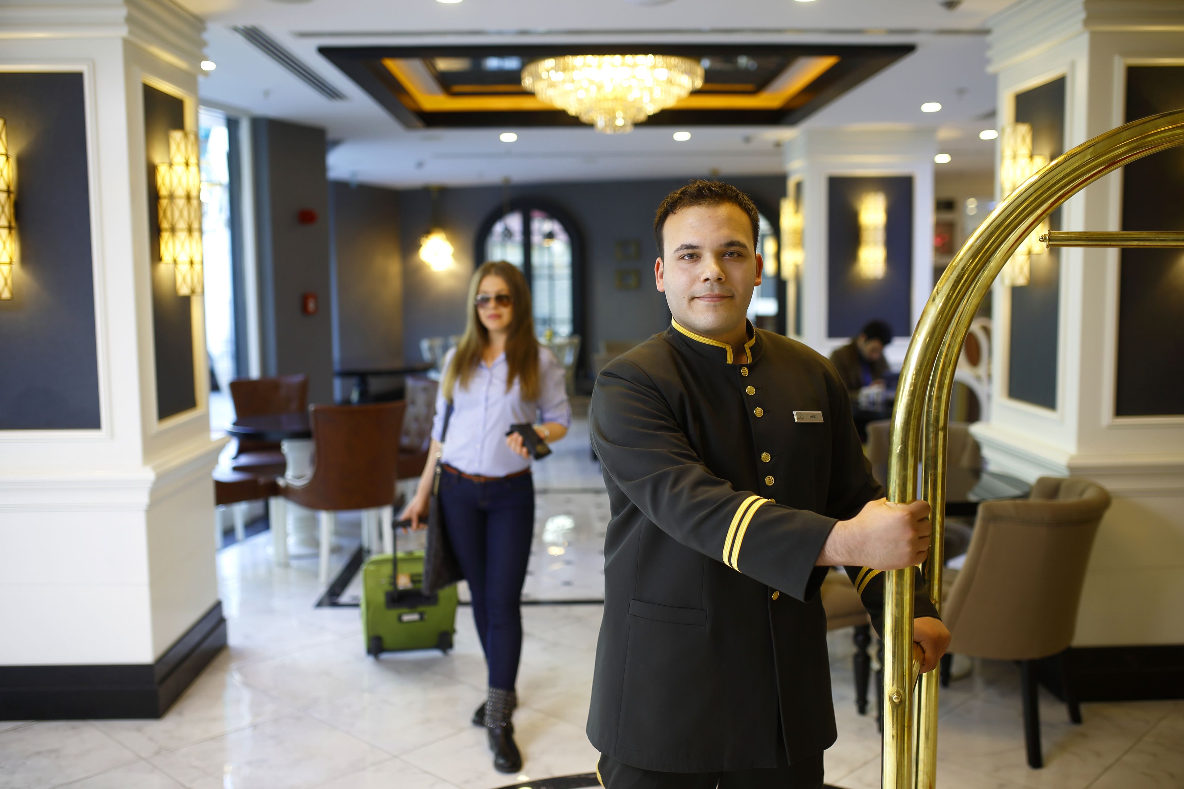 A hotel lobby with a grand chandelier, a reception desk, and a modern interior design.