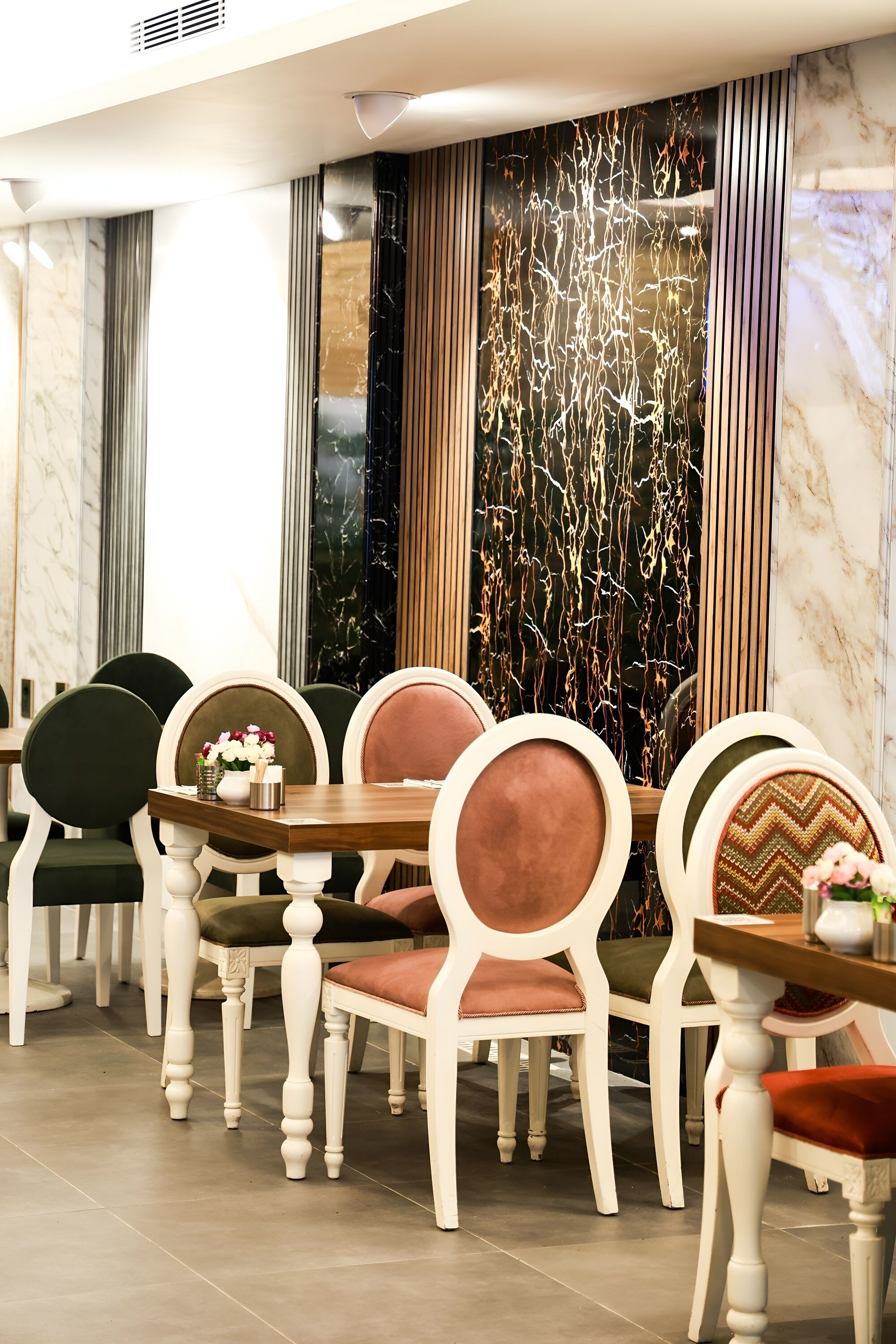 Un espace repas agrémenté d’un mur en marbre, d’un panneau décoratif et d’une table entourée de chaises.