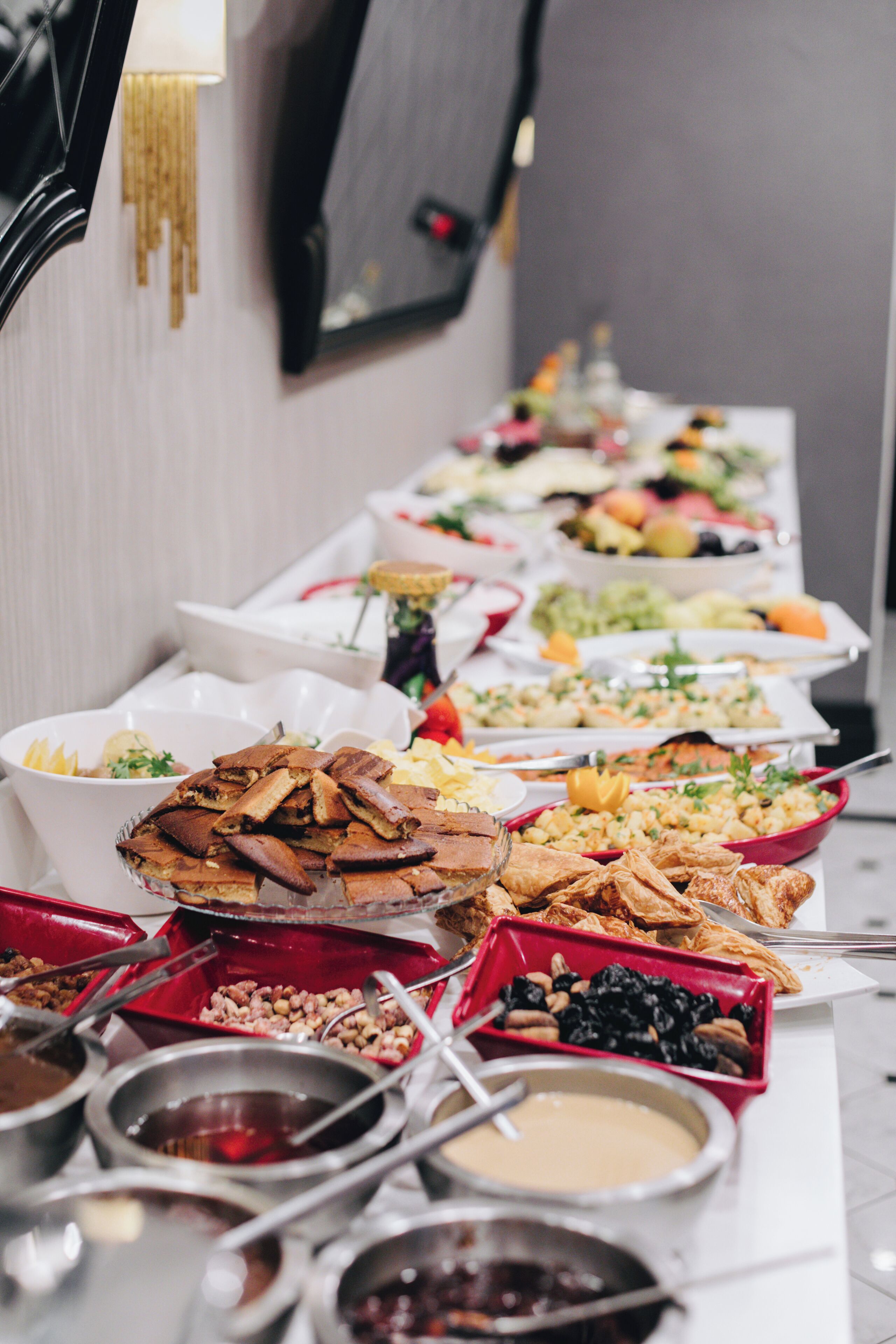 A buffet table with various food items and serving utensils.