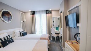 Une chambre d’hôtel avec deux lits, un bureau, une chaise, une télévision et un miroir.