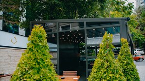 Un espace extérieur moderne aménagé avec une table et des bancs en bois, entouré d’arbustes verdoyants.