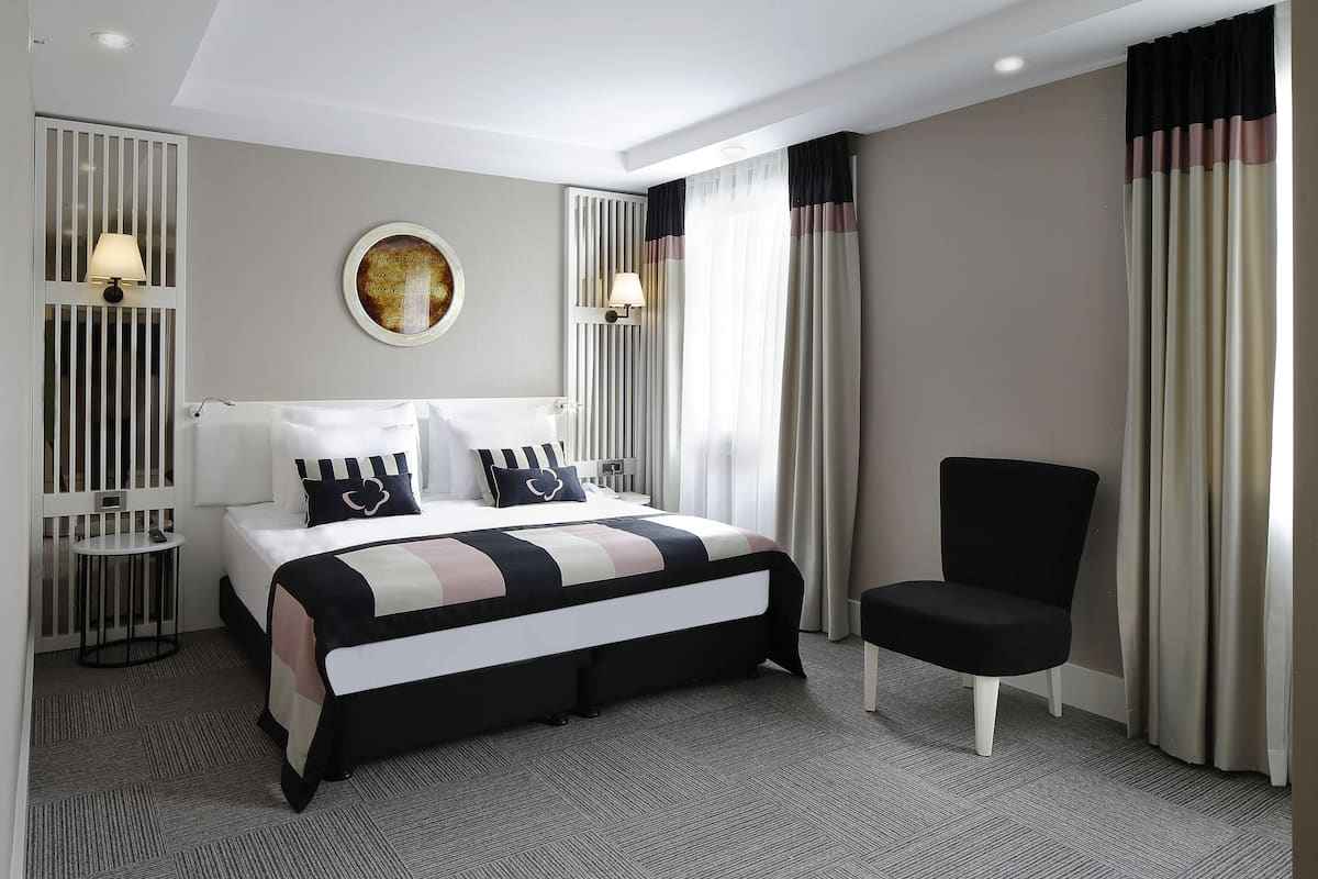 A modern hotel room with a neatly made bed, a chair, and a small table.
