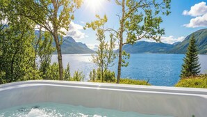 A hot tub with a view of a lake and mountains. - Arctic Panorama Lodge (Skjervoy)