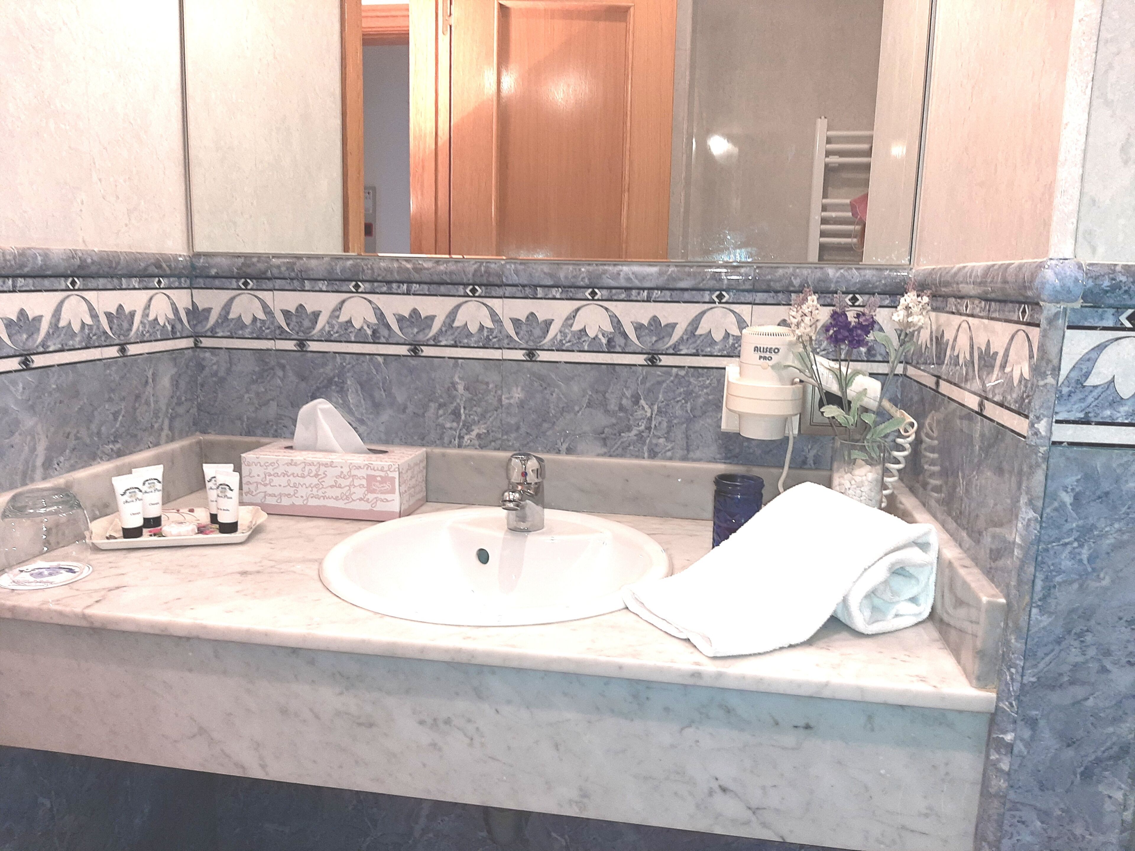 A bathroom with a marble sink, a towel, a tissue box, and toiletries.