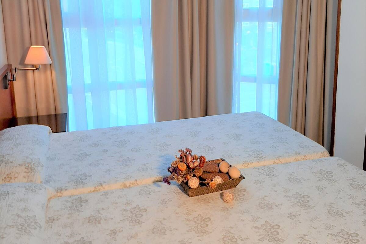 A hotel room with a bed, a lamp, and a window with curtains.
