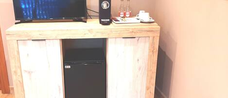 A wooden desk with a television, a black speaker, and two bottles of water.